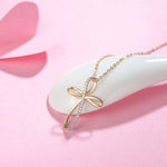 Delicate dainty gold necklace with ribbon inspired cross design